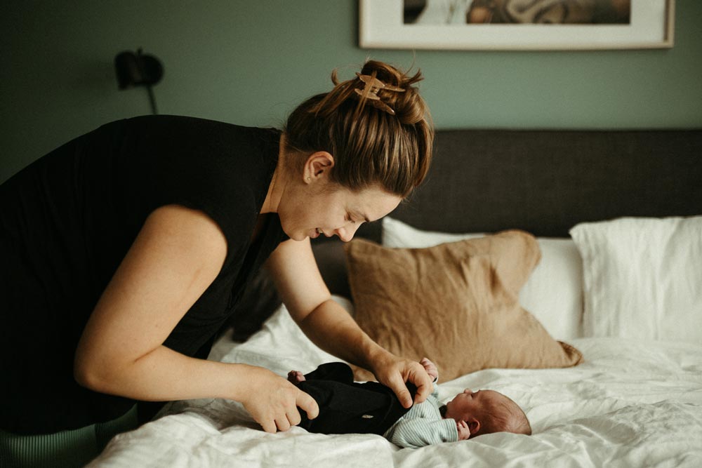 Mother dressing her newborn baby