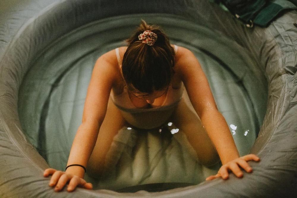 Kvinna som sitter i en pool vid födsel